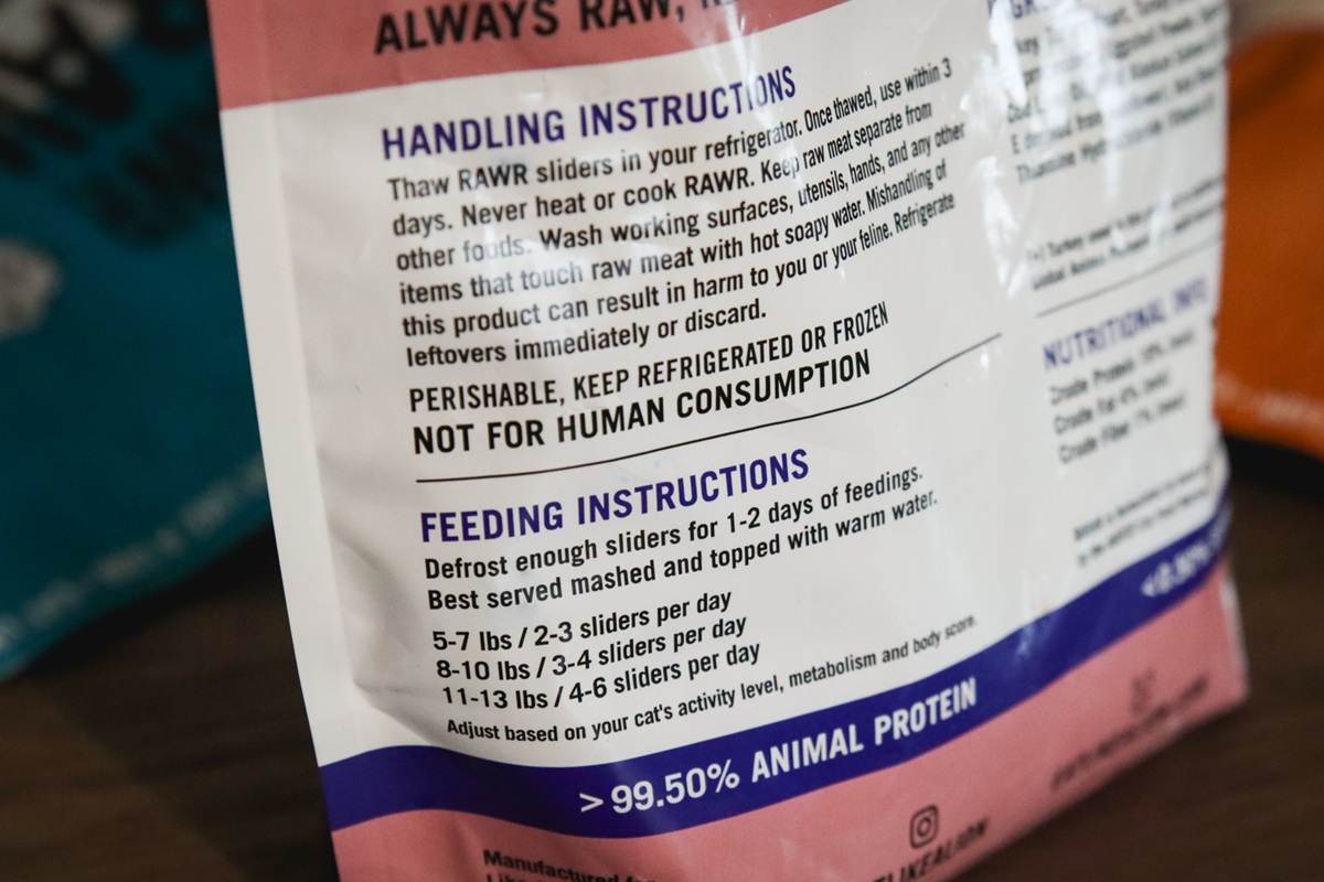 A close-up of a pet food package back panel showing feeding directions and calorie information, photographed in a home setting